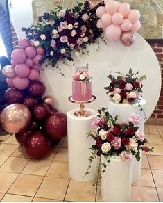 a table topped with three cakes covered in pink and white frosted cake next to balloons