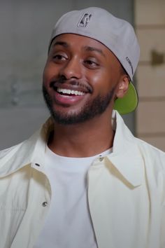 a close up of a person wearing a white shirt and a hat with green earrings