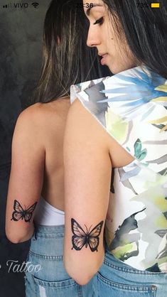 the back of a woman's shoulder with two butterflies on it and one is black