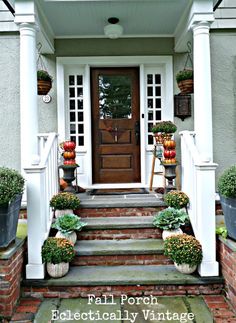 the front porch is decorated with potted plants and pumpkins on the steps to the door