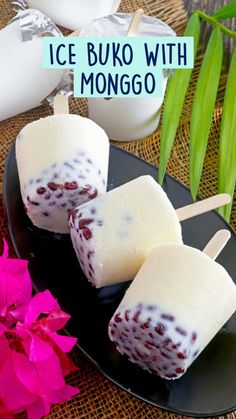 three popsicles on a black plate with pink flowers