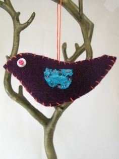 a bird ornament hanging from a tree branch with buttons on it's back