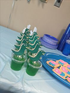 there are two cups with green liquid in front of the cupcakes on the table