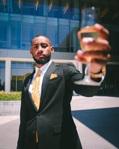 a man in a suit and tie holding up a wine glass with his right hand