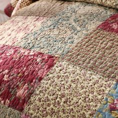 a bed covered in a colorful quilt and pillows