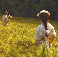 two people standing in a field with tall grass