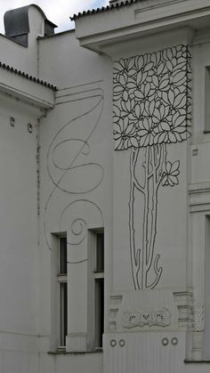 a white building with a tree painted on it's side and an ornamental window