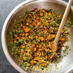 a large metal bowl filled with food and a wooden spoon on top of the bowl