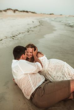 young newly engaged couple wearing white & beige snuggle,  laying half in, half out of the water in St. Andrews State park, PCB Florida.  Portrait captured by Brittney Stanley of Be Seen Photos Pcb Florida, Proposal Beach, Photography Poses Couples, Couples Photography Poses, Beach Proposal, Poses Couples, Panama City Beach Fl, Panama City Beach Florida, Mexico Beach