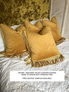 three yellow pillows on top of a bed with fringes and text that reads comfy / mustard velvet cushion covers made to order with fronging trim