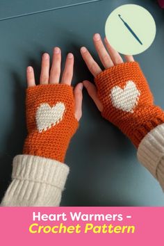 two hands wearing knitted mittens with white hearts on them and one hand holding the other