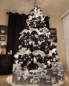 a black and white christmas tree with presents under the tree, decorated with silver ribbon