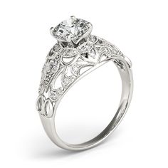 a white gold engagement ring with an oval center stone and filigrees on the sides