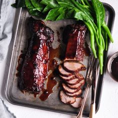 meat and vegetables on a tray with sauce