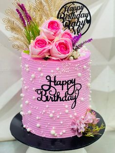 a pink birthday cake with flowers and feathers on top is decorated with the words happy birthday