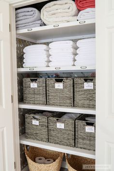 an organized closet with baskets and towels