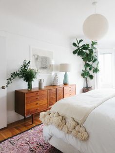 a bed room with a neatly made bed next to a window and a wooden dresser