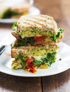 two sandwiches stacked on top of each other on a plate with a knife and fork