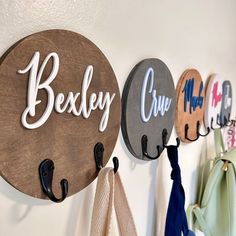 there are three hooks on the wall holding coats and umbrellas that say bexley cru