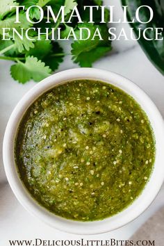 a white bowl filled with pesto sauce next to cilantro and parsley