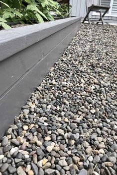 a graveled walkway next to a house with a lawn chair on the other side