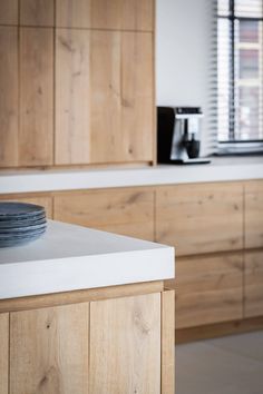 a kitchen with wooden cabinets and plates on the counter top in front of a window