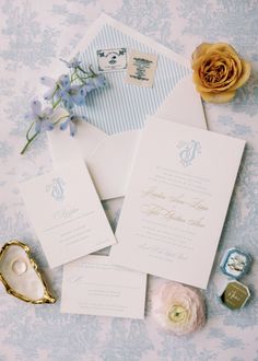 the wedding stationery is laid out on top of the blue and white tablecloth