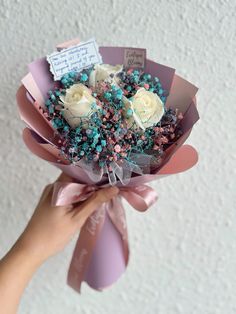 a person holding a bouquet of flowers with tags on it's stems and ribbons