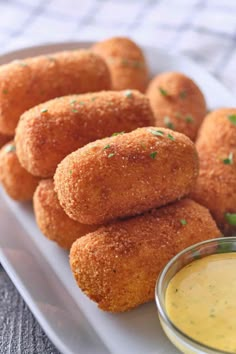 some fried food on a white plate with dipping sauce