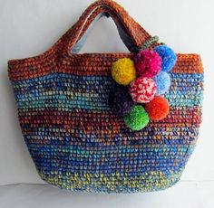 a multicolored bag with pom - poms hanging from it