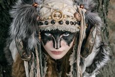 a woman with black and white face paint wearing a headdress made of feathers