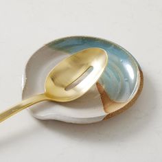 a gold spoon sitting on top of a blue and white plate with the words west elm written below it