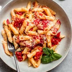 pasta with tomato sauce and parmesan cheese in a white bowl on a table