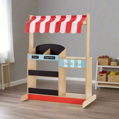 a wooden toy stand with a black and red striped awning