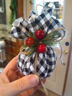 a person holding up a christmas ornament with two cherries hanging from it