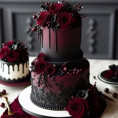 three tiered black and white cake with red roses on top, sitting on a table