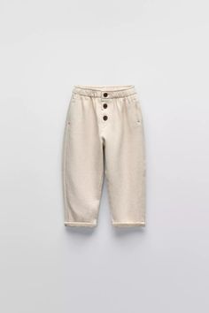 Relaxed Fit Beige Pants With Button Closure, Beige Relaxed Fit Pants With Button Closure, Casual Cotton Pants With Buttoned Pockets, Beige Relaxed Fit Bottoms With Button Closure, Cream Cotton Straight Pants, Beige High-waisted Pants With Patch Pockets, Classic Neutral Bottoms With Pockets, Casual Straight Pants With Button Cuffs, Cream High-waisted Jeans