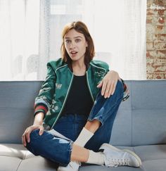 a woman sitting on top of a couch in front of a window with her legs crossed