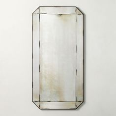 a mirror hanging on the wall in front of a white wall