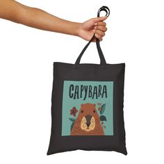 🌟 Embark on an adventure with our Capybara Cotton Canvas Tote Bag! 🎨 Crafted from premium cotton canvas, this tote adds a touch of rugged charm to your travel essentials. Whether you're exploring city streets or venturing into the great outdoors, let the adorable hand-drawn capybara illustration accompany you on your journey! 🌿 Inspired by nature's gentle giant, this tote features a charming capybara design that's sure to bring a smile to your face. With dimensions of 15" x 16", it offers amp Black Cotton Bag For Outdoor, Black Cotton Outdoor Bag, Outdoor Black Cotton Bag, Black Canvas Tote Bag For Outdoor, Black Casual Canvas Bag For Outdoor Activities, Casual Black Canvas Bag For Outdoor Activities, Outdoor Black Canvas Bag, Capybara Illustration, Explore City