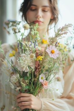 a woman holding a bouquet of flowers in her hands