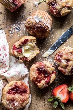 strawberry muffins with powdered sugar and fresh strawberries next to them on a cutting board