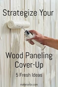 Hand painting over wood paneling with a white paint roller. Text reads: "Strategize Your Wood Paneling Cover-Up - 5 Fresh Ideas". Wood Paneling Wallpaper, Cover Up Wood Paneling, Covering Paneling Walls Ideas, Update Wood Paneling, Paneling Walls Makeover, Painting Paneling Walls, Wood Paneling Walls, Painting Fake Wood, Paint Over Wood Paneling