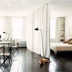 a cat laying on the floor next to a bed in a room with white walls