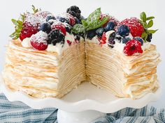 a layered cake with berries and powdered sugar on top