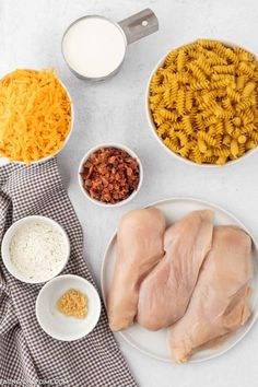 ingredients to make chicken parmesan pasta laid out on a white counter top with bowls and utensils