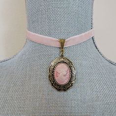 Pink velvet ribbon is linked with a lovely lady cameo pendant set on an antique gold ornate filigree oval setting and linked on a matching slider bail.  The ribbon is crimped with matching metal bars and the length of the choker is 13 " on first link closure.  Choker has an extension chain which makes for an adjustable fit up to 15 " neck measurement with the hook closure. There is a gold leaf bead dangle accent on the extension chain.   All of my jewelry items come boxed, and ribbon tied and tagged for easy gifting. Vintage Cameo Choker Necklace, Cameo Choker, Pink Velvet Ribbon, Oval Setting, Victorian Costume, Cameo Jewelry, Pendant Choker, Cameo Necklace, Cameo Pendant