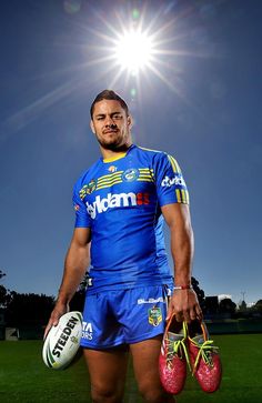 a rugby player is posing for a photo with his ball and gloves in front of the sun