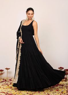 *Immerse yourself in the sophistication of this solid black Anarkali kurta, designed to be both a statement piece and a canvas for your individual style.  *The round neckline of the Anarkali kurta is an embodiment of classic charm, elegantly fitted at the bust to enhance your natural silhouette.  *The coordinating dupatta, adorned with intricate gotta work along the border, adds a touch of artisanal flair.  *It is not just an accessory; it's a complementary masterpiece that frames the ensemble w Traditional Black Gown With Zari Work, Black Georgette Anarkali Set For Eid, Black Georgette Anarkali Set For Navratri, Black Georgette Dress For Festivals, Semi-stitched Black Gown For Eid, Black Semi-stitched Traditional Gown, Black Traditional Semi-stitched Gown, Eid Black Georgette Anarkali Set, Navratri Black Georgette Anarkali Set