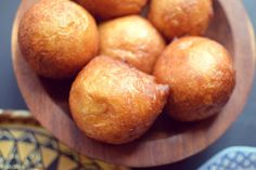 a wooden bowl filled with doughnuts on top of a table